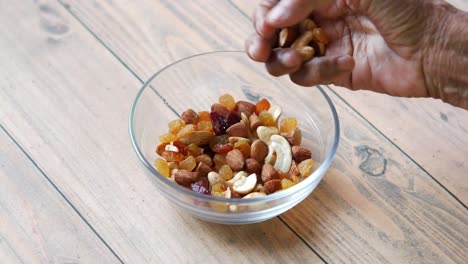 elderly hand mixing nuts and dried fruit