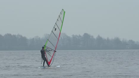 Person-kite-surfing-on-foggy-day-in-local-lake-and-falls-down,-handheld-follow-up-view