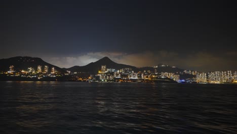 Aufnahme-Von-Einem-Boot-Aus,-Das-Mitten-In-Der-Nacht-Links-Von-Einer-Urbanisierten-Insel-Fährt-2