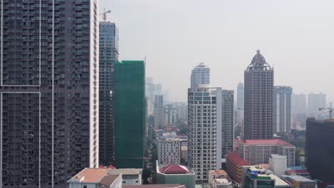 phnom penh city skyline buildings construction, multi storey residential housing buildings complex under hazy sky, smog due to air pollution, aerial view