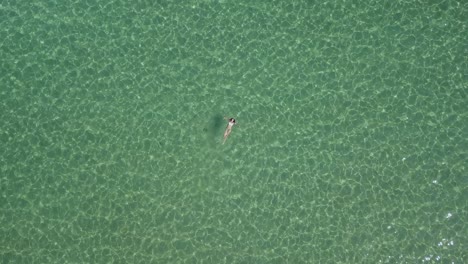 a brown haired woman splashes and swims in the clear waters off paros island in greece