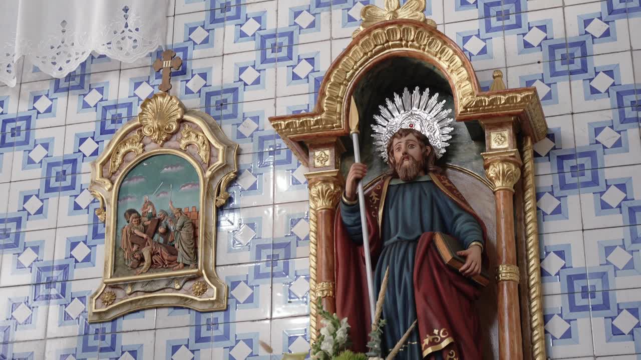 Statua religiosa di un santo con un'aureola su una parete decorata di una chiesa con piastrelle blu