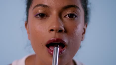 Close-up of woman applying lipstick and blowing kiss to camera.
