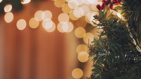 mujer de mano decorando el árbol de navidad con luces navideñas.