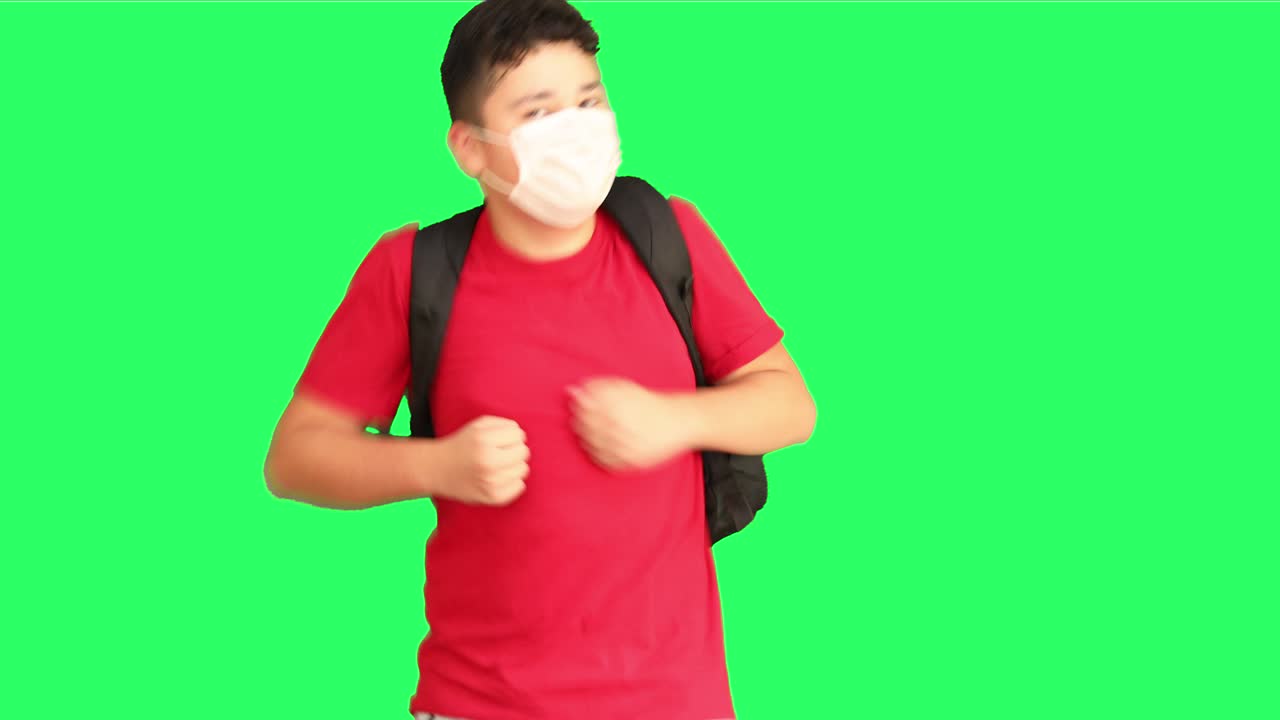 녹색 스크린에서 달리는 의료 마스크를 입은 어린 소년