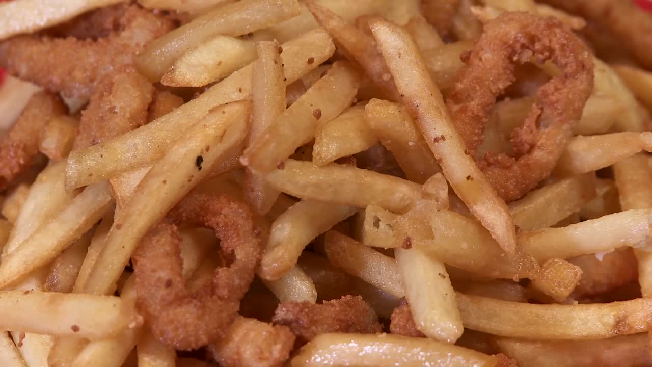 un plato de papas fritas grasosas y aros de cebolla sugiere comer alimentos grasosos en exceso