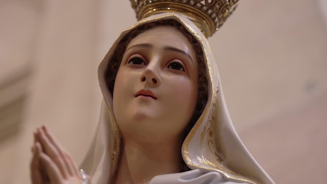 detailed close up of virgin mary statue wearing crown and white robe in prayer