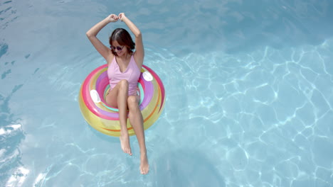 Happy woman on pool float in swimming pool in sunglasses, copy space