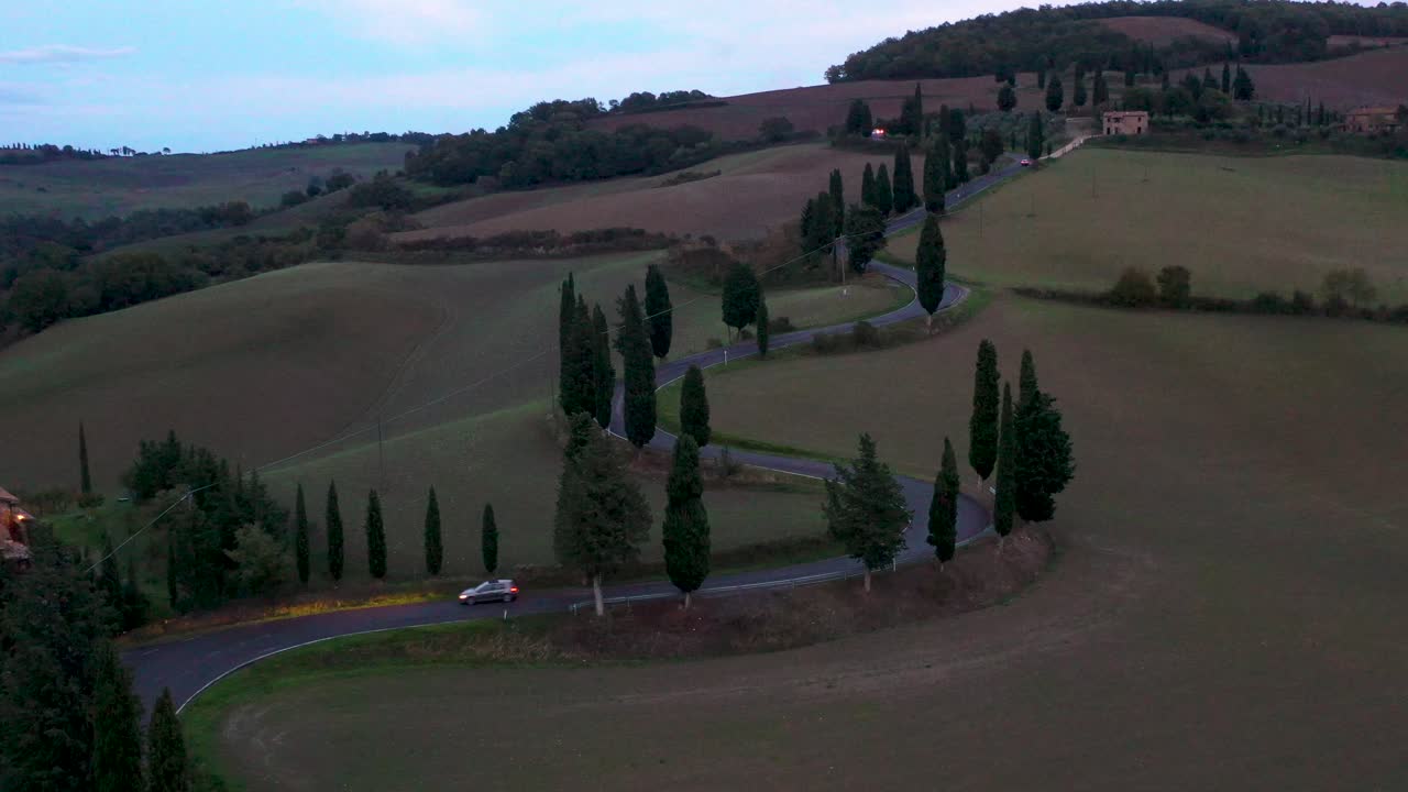 vening Drone aerial footage of a car moving on empty Road Curve in autumn  in Tuscany, Italy. Environment, traveling, car sharing concept