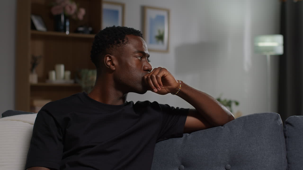 joven infeliz y deprimido sentado en el sofá en casa mirando ansioso y preocupado descansando la cabeza en la mano 3