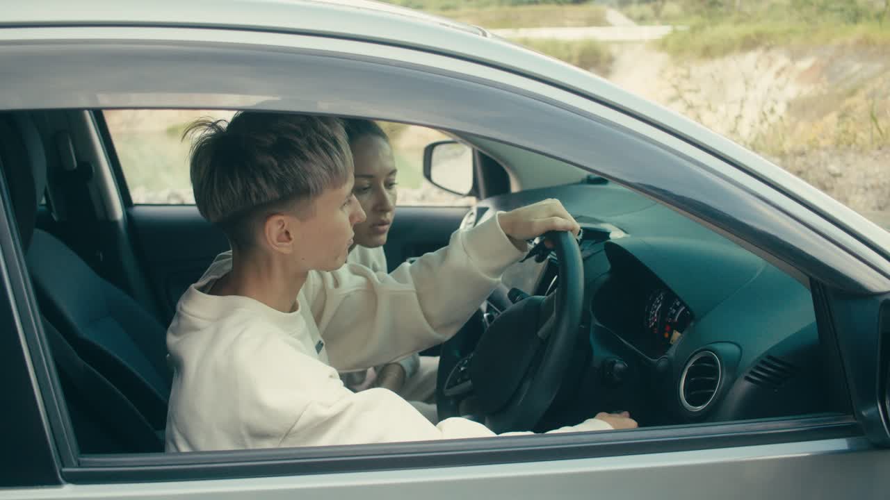 Two people in a car, with one person instructing or assisting the other with driving.