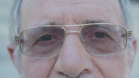 primer plano de los ojos de un anciano en gafas mirando a la cámara