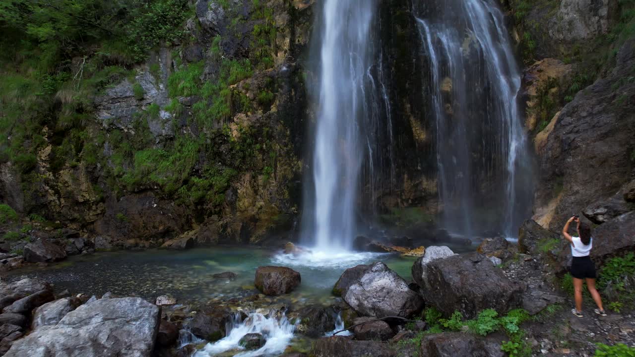 mujer turista tomando fotos en la hermosa cascada de montaña en theth, albania