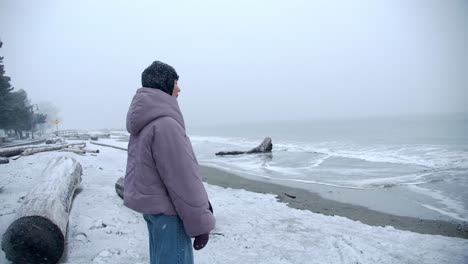 woman standing on the beach on a snowy winter day slow motion