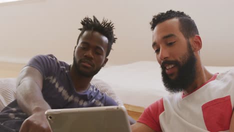 Two-young-male-friends-fist-bumping-each-other-while-looking-in-the-digital-tablet