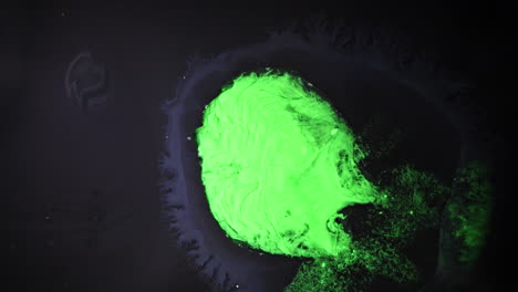 substances mixing with vibrant green color in a dark fluid, macro shot