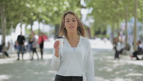 Attractive-girl-with-paper-cup-walking-on-street