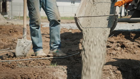 Pouring-Concrete-Into-The-Foundation-From-The-Gutter-Concrete-Flows-Next-To-The-Worker-With-A-Shovel