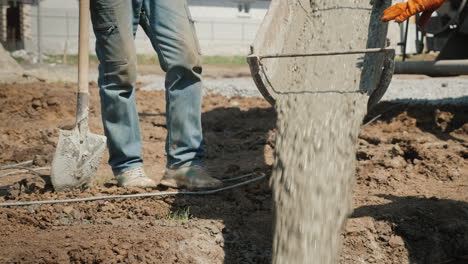 pouring concrete into the foundation from the gutter concrete flows next to the worker with a shovel