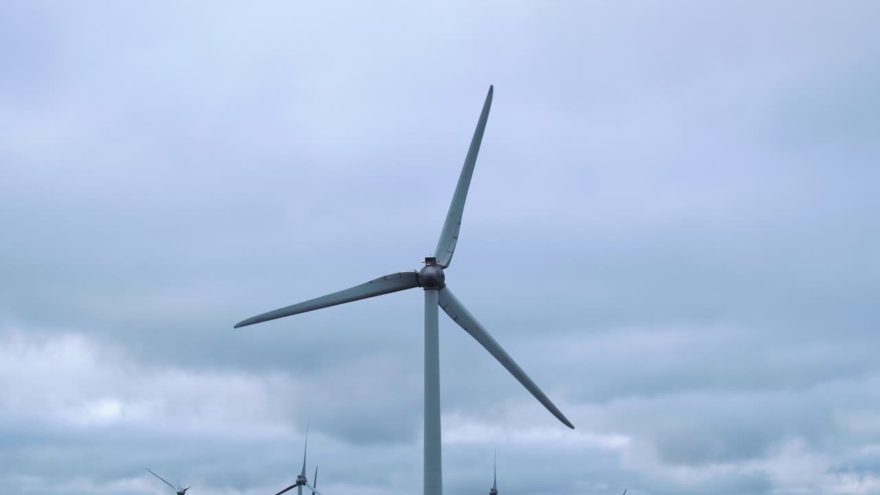 Close up windmill rotate propeller slowly producing green sustainable energy for the future generations, cloudy rain sky background