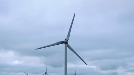 Close up windmill rotate propeller slowly producing green sustainable energy for the future generations, cloudy rain sky background