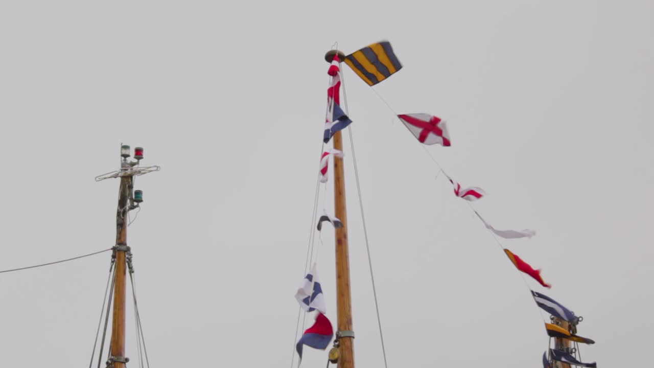 banderas de vela náuticas coloridas volando en el viento desde las líneas de un mástil de velero en un día nublado