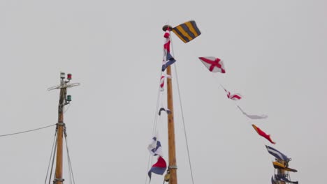 colorful nautical sailing flags flying in the wind from the lines of a sailboat mast in a cloudy day