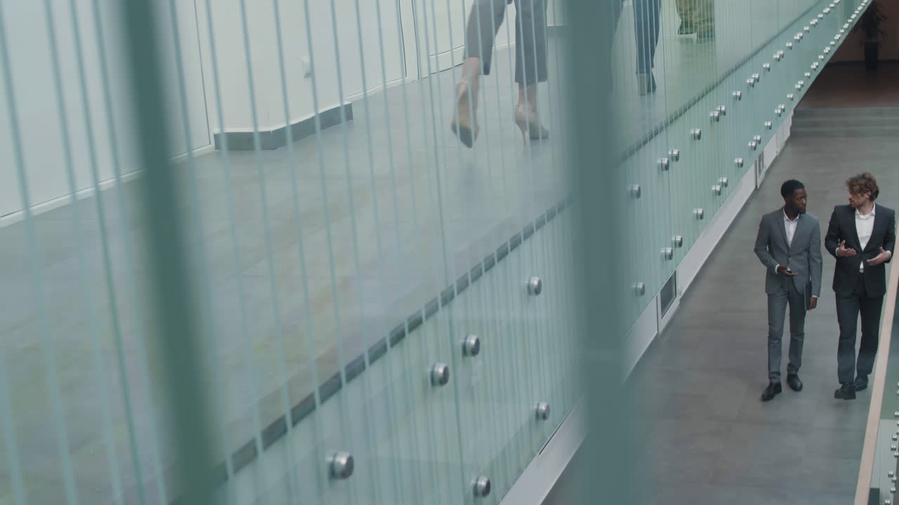 dos hombres de negocios que van a lo largo de la sala de la oficina y se comunican