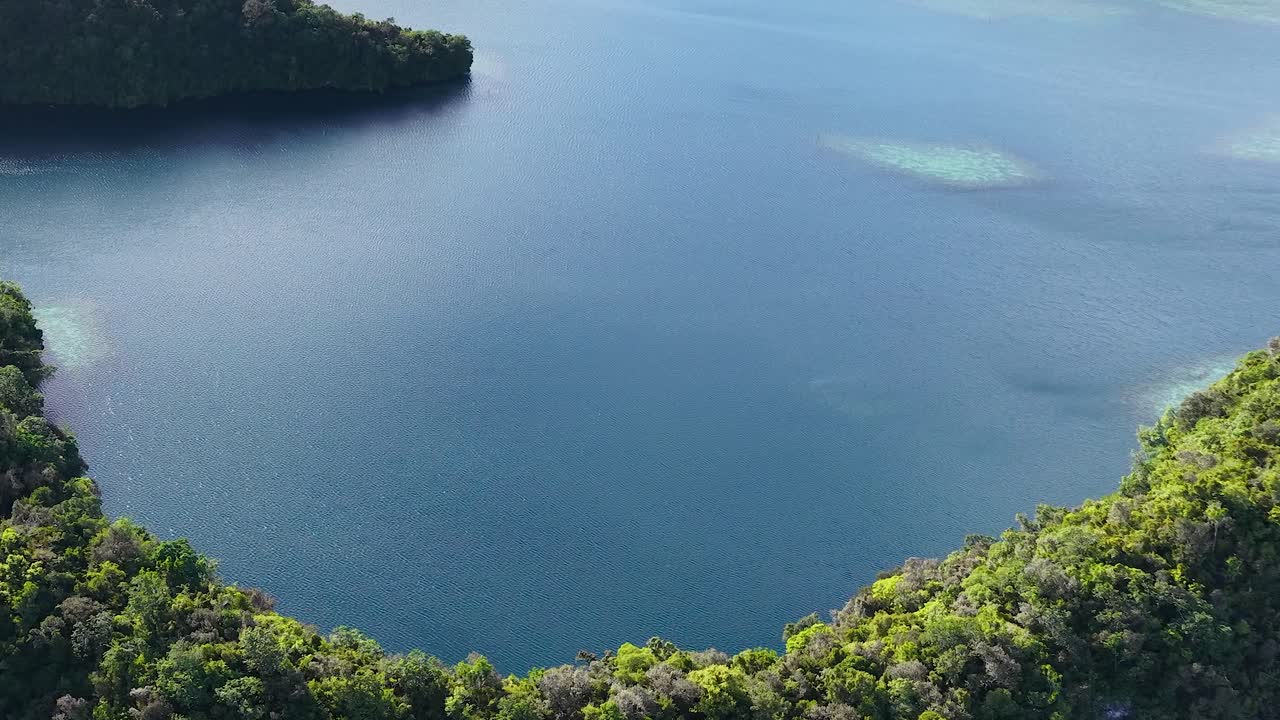 Cảnh quay drone góc cao bay qua những hòn đảo nhiệt đới xanh tươi và mặt nước xanh ngọc bích êm ả ở Palau.