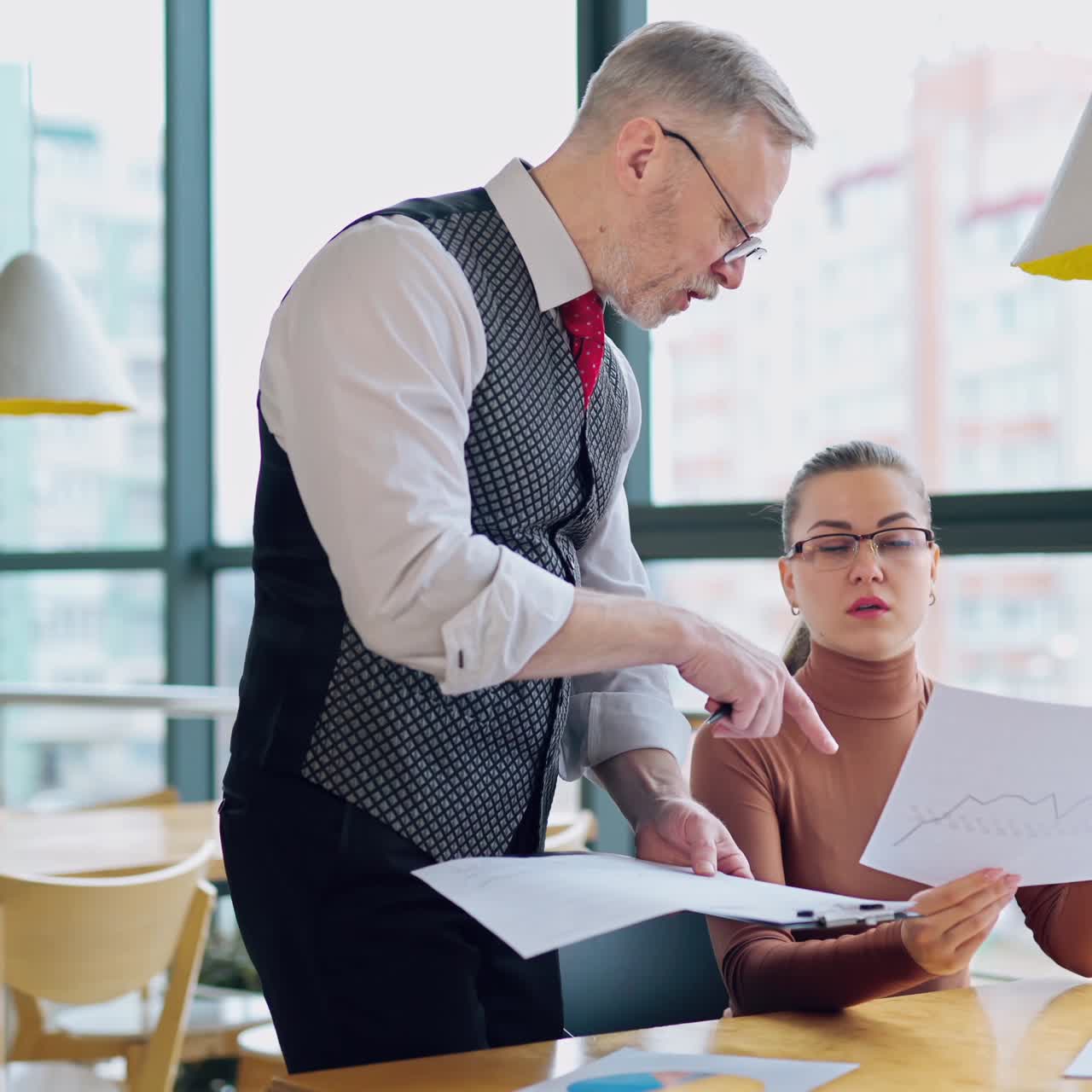 Young businesswoman and senior businessman working together in a light room with big windows. Team work. Business video
