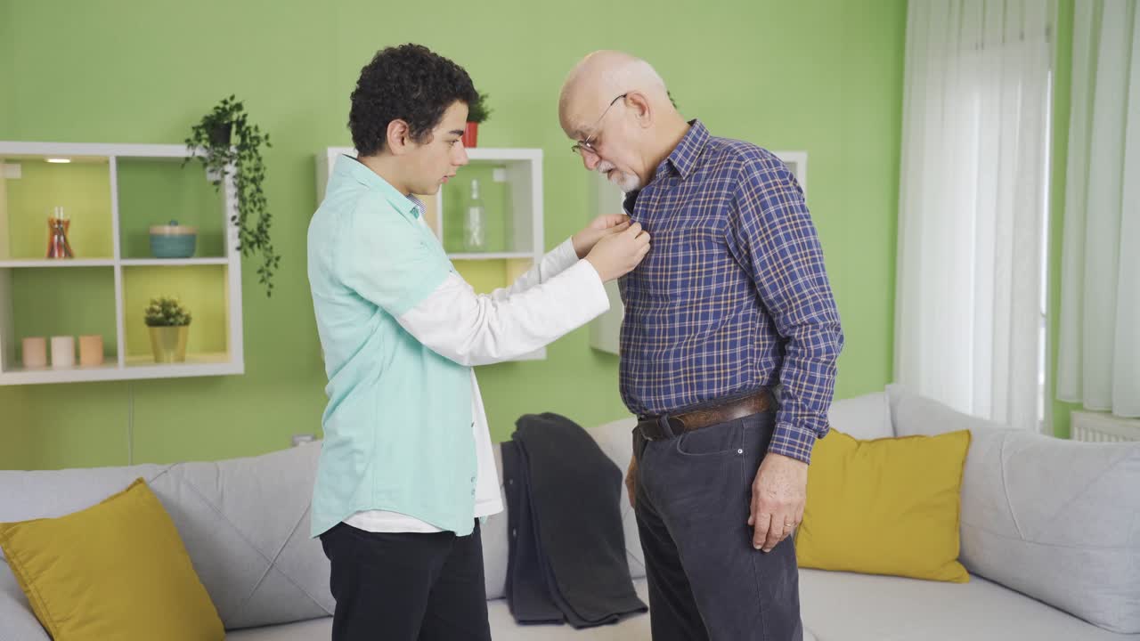 손자가 아픈 할아버지를 도와 옷을  ⁇ 고 있습니다.