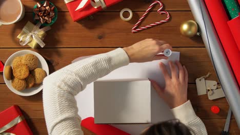 Frau-Zeigt-Weihnachtsgeschenk-In-Kraftpapier-Mit-Roter-Schleife.-Vertikales-Video.-Frau-Zeigt-Weihnachtsgeschenk-In-Kraftpapier-Mit-Roter-Schleife.-Lächelnde-Frau-Hält-Neujahrsgeschenkbox.-Frohe-Weihnachten-Oder-Ein-Glückliches-Neues-Jahr-2025-Feiern.-Vertikales-Video