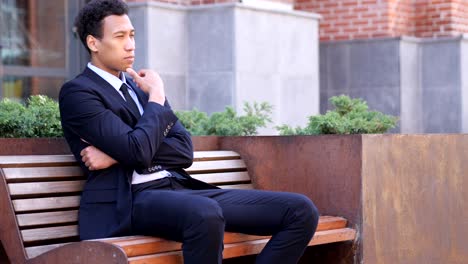 pensive serious african businessman sitting on bench