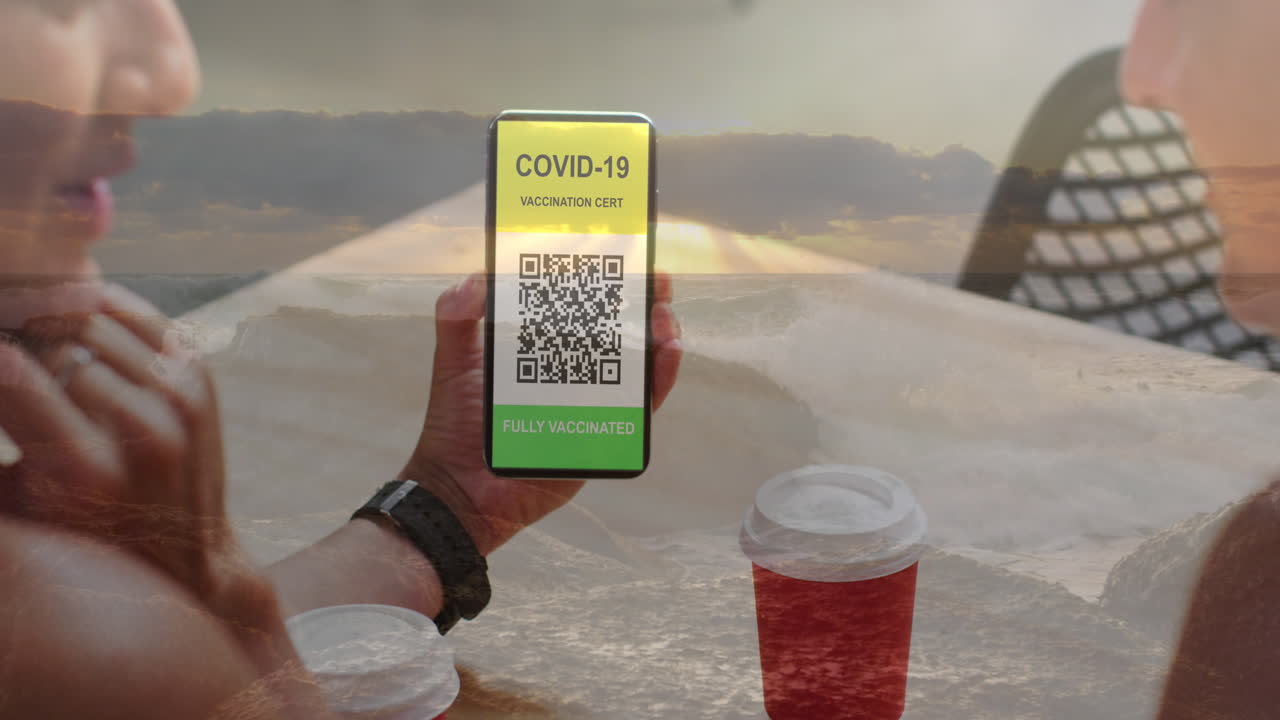 Composition of woman holding a smartphone with qr code on screen against sea waves hitting the rocks