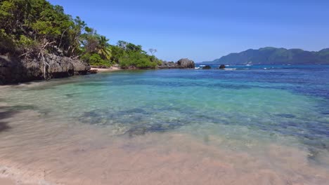 pov camina en la playa de arena en las aguas claras de la bahía en samaná durante un día soleado con cielo azul