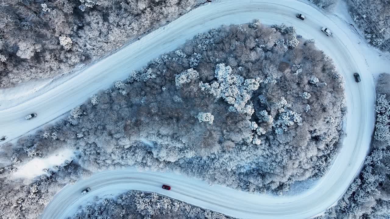 Aerial View of a Winding Snowy Mountain Road with Cars