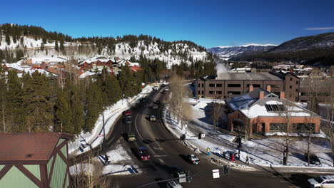 aerial view with orbit ascending of road passing though snowy mountain with cars and people walking