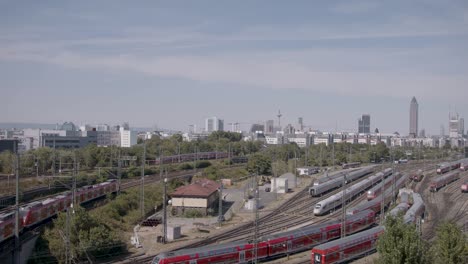 vista panorámica de la estación de tren de frankfurt con múltiples trenes y el horizonte urbano en el fondo, de día