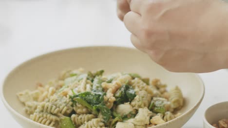 chef adding walnuts to pasta on plate