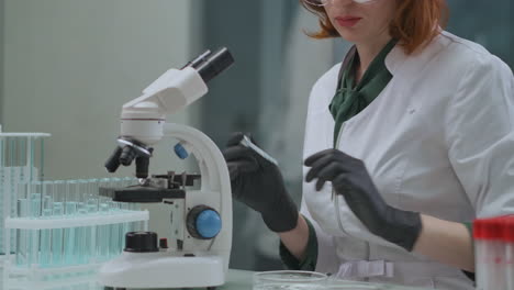 female-technician-is-researching-analysis-in-lab-using-test-tubes-with-liquids-and-microscope-quality-control-at-production-and-ecological-expertise