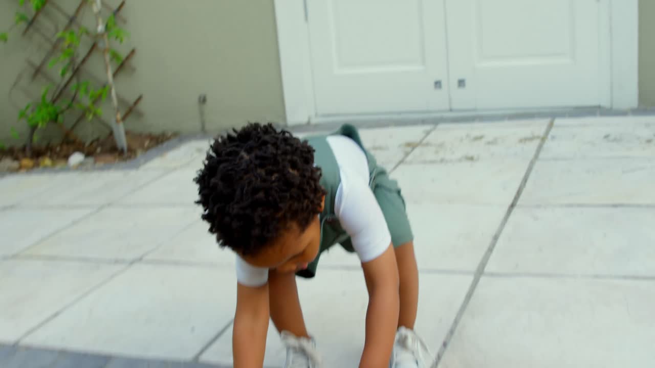 Vista frontale di un simpatico bambino nero che gioca nel giardino di casa sua 4k