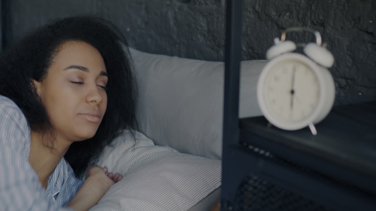 알람 시계와 함께 침대에서 잠자는 여자