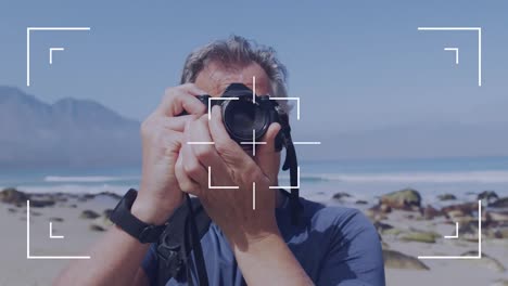 camera user interface frame and focus screen over caucasian senior man by the sea taking photos