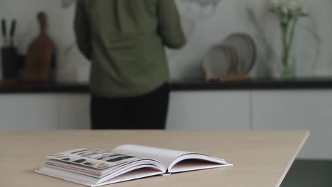 la persona está lavando los platos mientras se vuelve a la mesa con papel de revista sobre ella