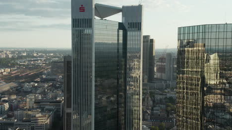 AERIAL:-Flight-around-Frankfurt-am-Main,-Germany-Skyscraper-reflecting-in-Sunlight-in-June-2020