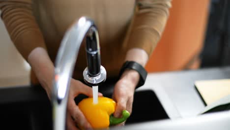 Man-washing-capsicum-under-water-tap-4k