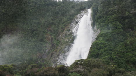 Giant-waterfall-cascades-dramatically-into-the-pristine-waters-of-Milford-Sound,-New-Zealand