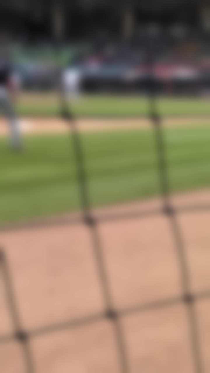 Un allenatore di baseball cammina lungo la linea di foul dopo un lancio.