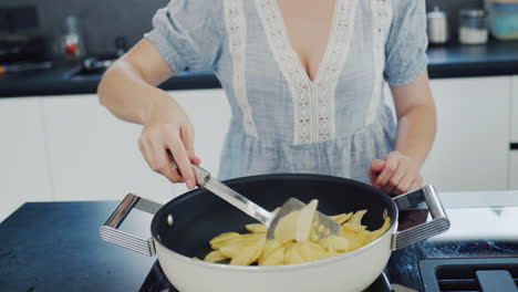 Young-beautiful-woman-fries-potatoes-on-an-electric-stove-with-a-built-in-hood