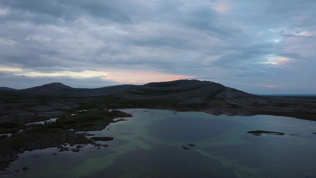 Early morning light illuminates the still waters and rugged hills of The Burren. Perfect for projects focusing on natural landscapes and serene environments.